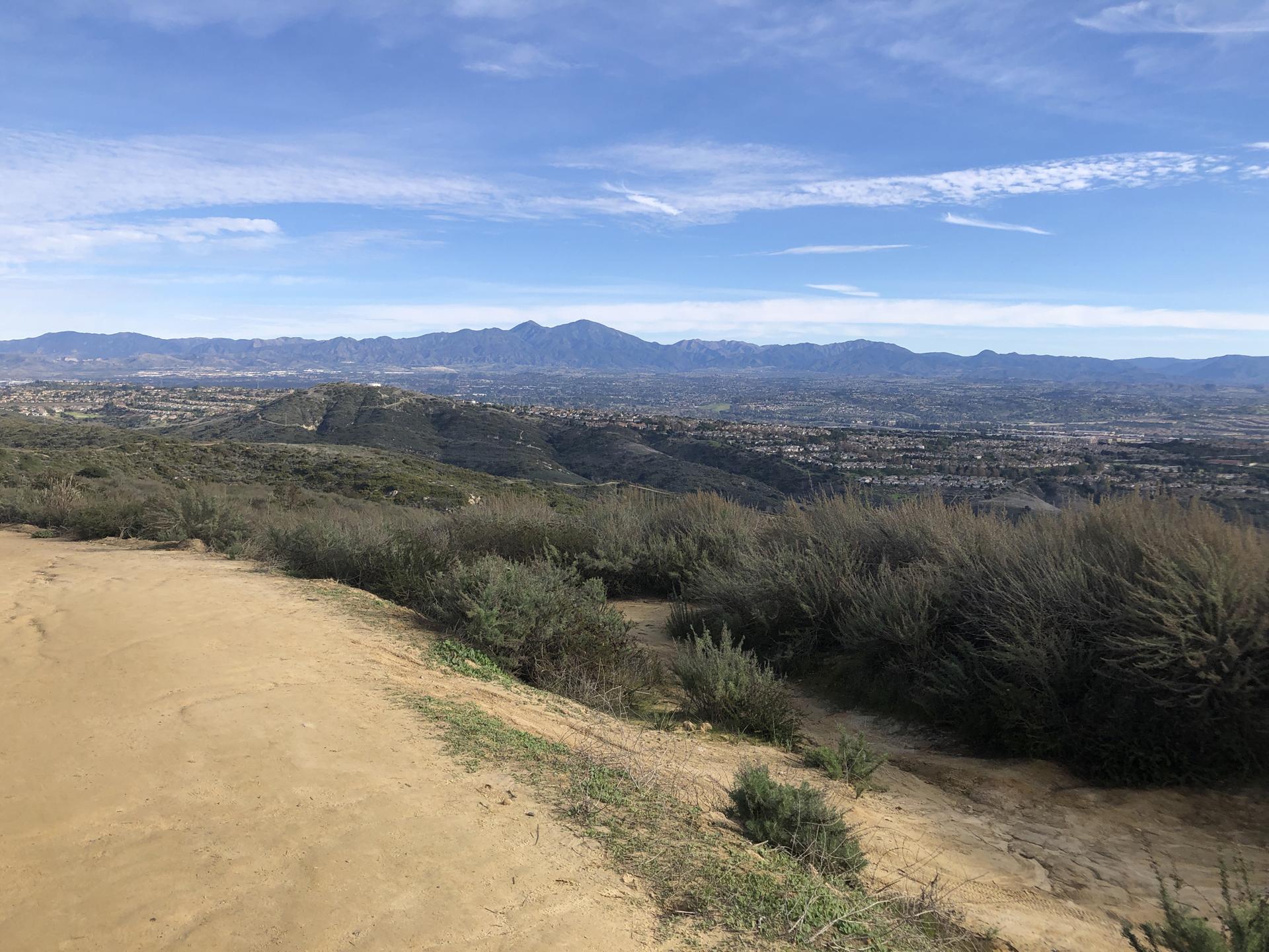 Panoramic view of a vast valley with distant mountains under a blue sky.