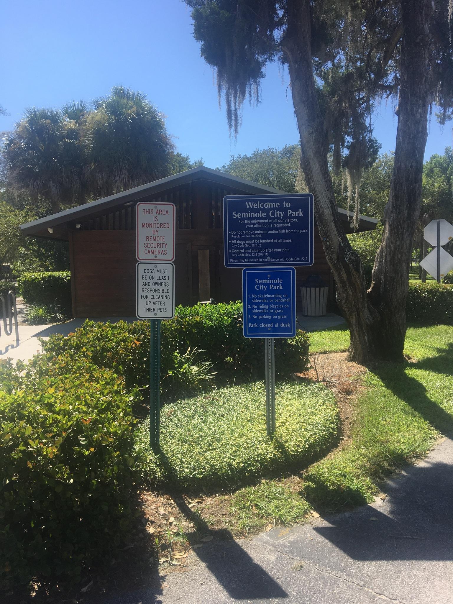 Park signs in front of a wooden building and trees on a sunny day.
