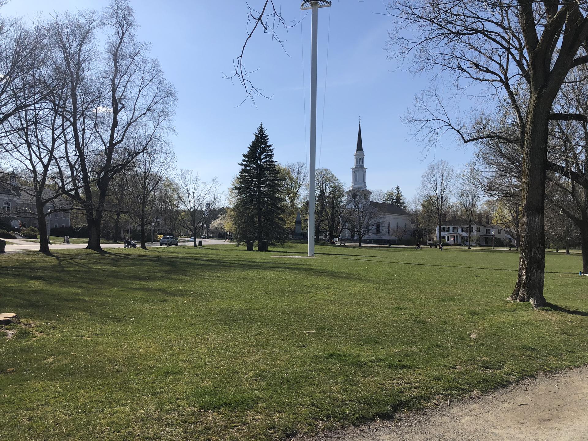 Wide grassy field with bare trees and a distant white church steeple.