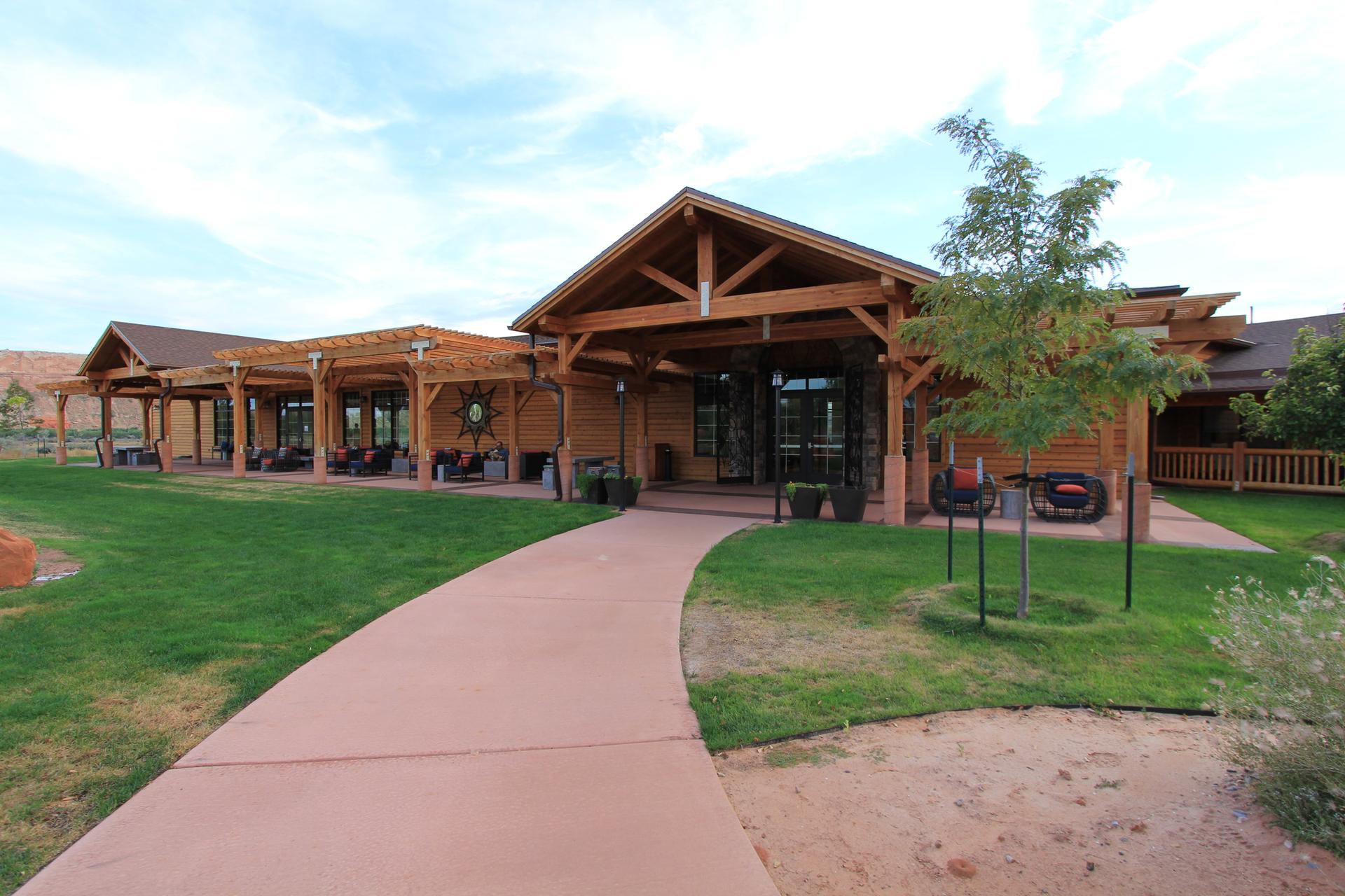 A wooden lodge building with a green lawn and paved walkway.