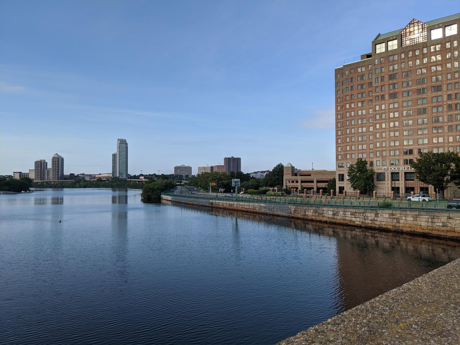 A wide river with distant city buildings under a clear blue sky.