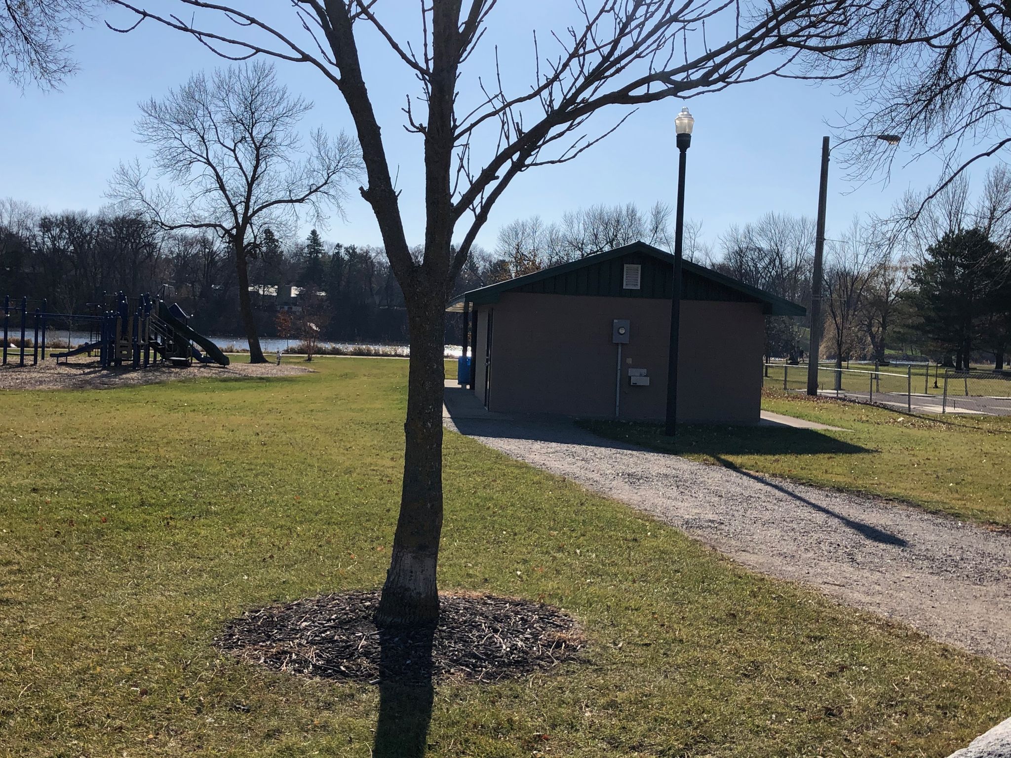 Small building in a park with a playground and bare trees. - Riverside Park – Oddfellows Park loop from Hutchinson