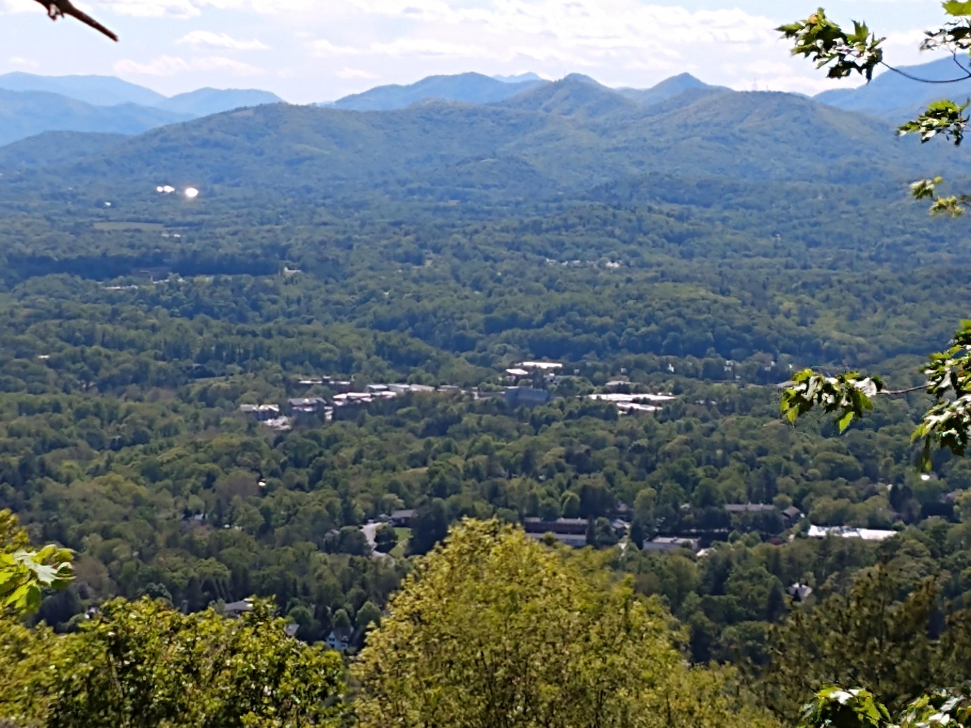 An expansive aerial view of a green forested valley with distant mountains.