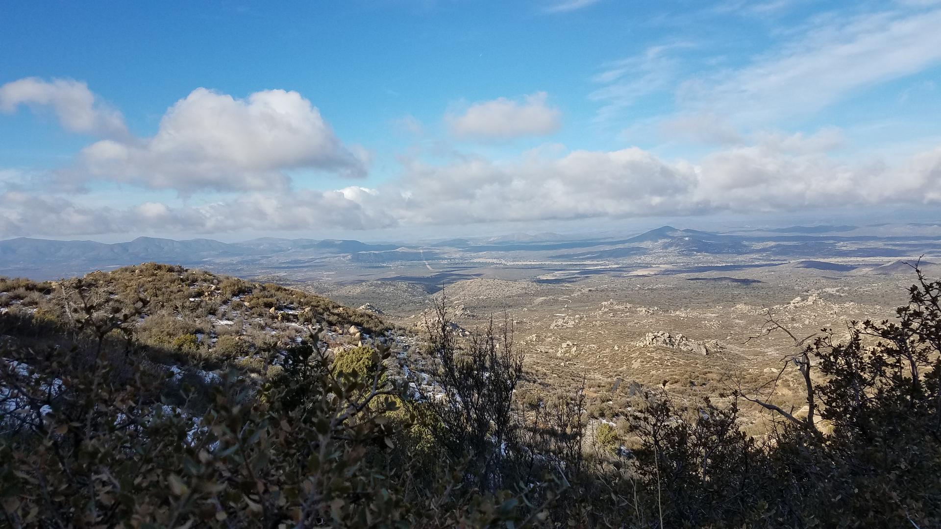 Panoramic view of a vast, dry landscape with distant mountains under a cloudy sky.