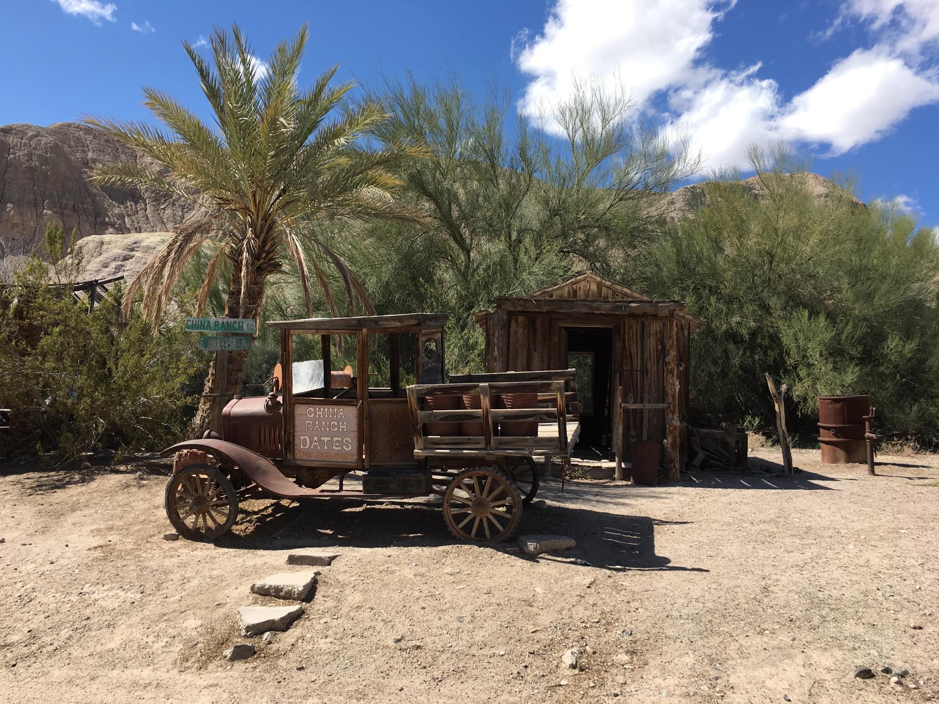 Old rusty truck and wooden shack under a bright desert sky.