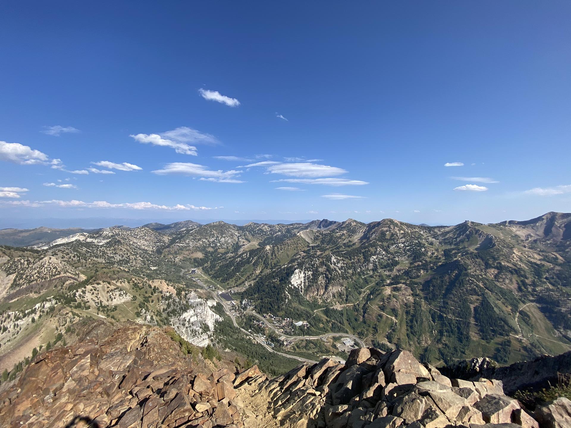 Vast mountain range under a bright blue sky with rocky foreground.