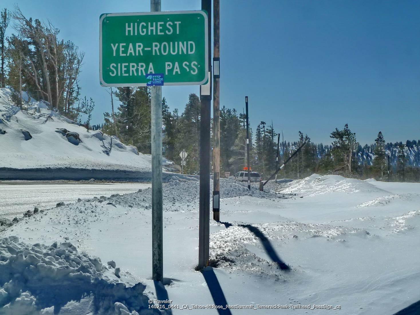 Green road sign standing in deep snow on a bright, clear day.