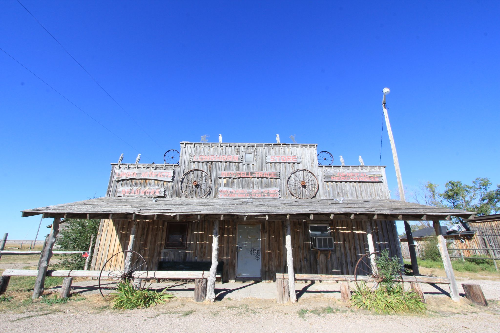 Rustic wooden building with wagon wheels under a clear, bright blue sky. - Scenic Ghost Town