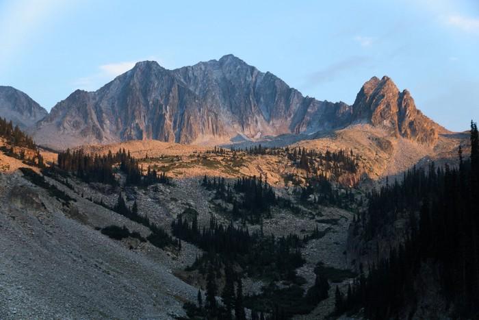 Majestic mountains and a forested valley bathed in golden hour light.