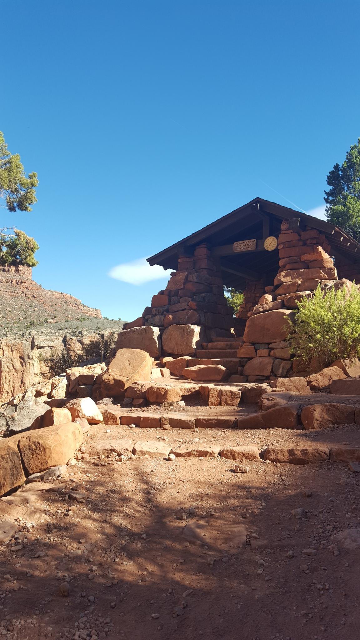 Stone building on a rocky path with steps under a clear blue sky.