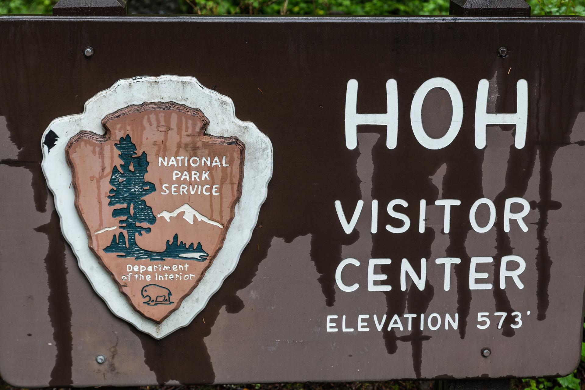 Wet brown sign with National Park Service emblem and white text.