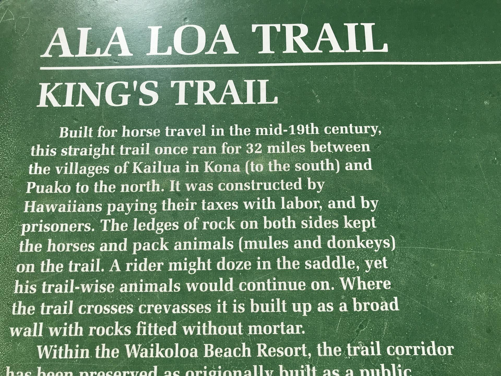Close-up of a green informational sign with white text about a trail.