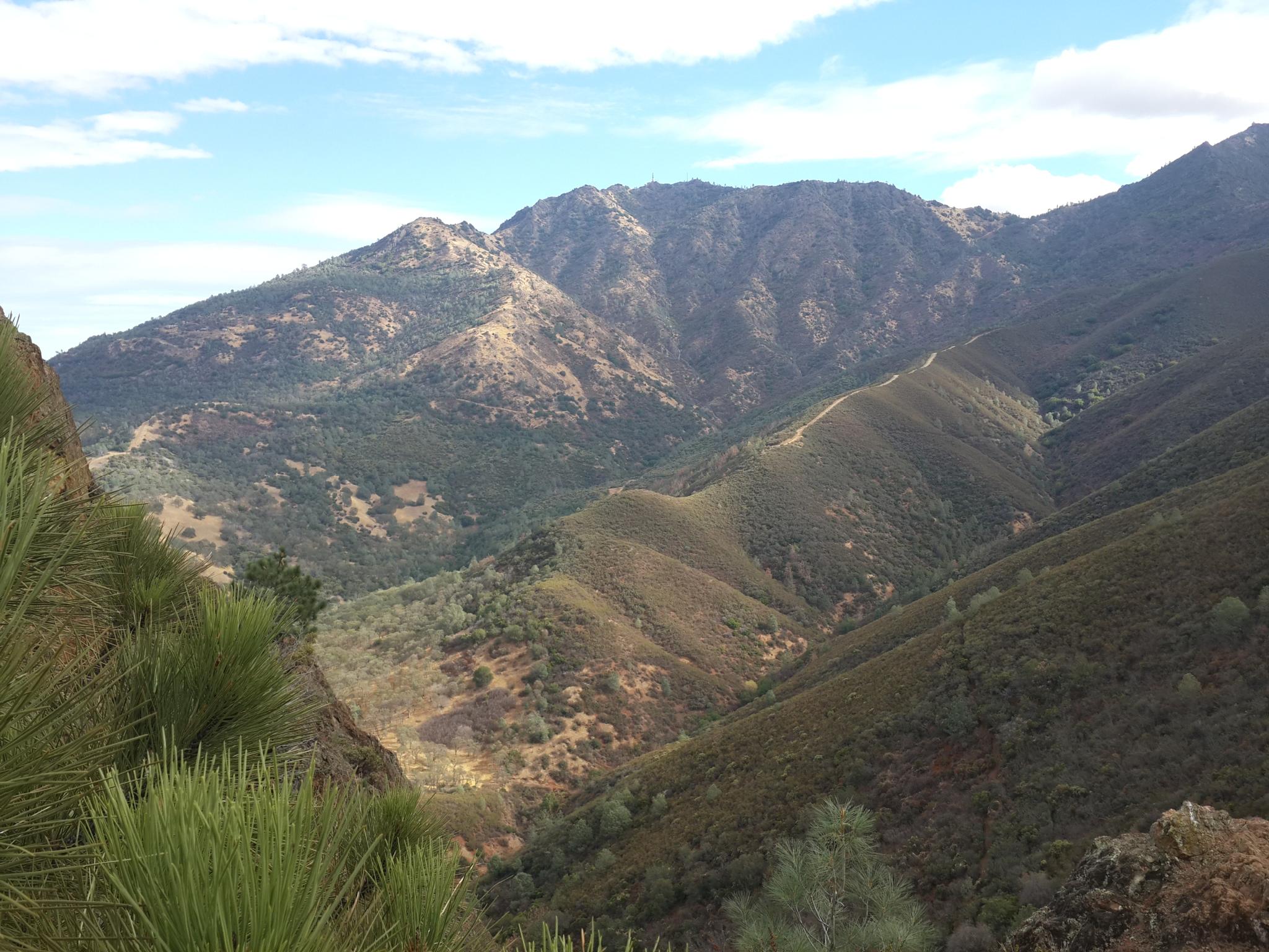 Deep valley with forested mountains and ridges under a partly cloudy sky.