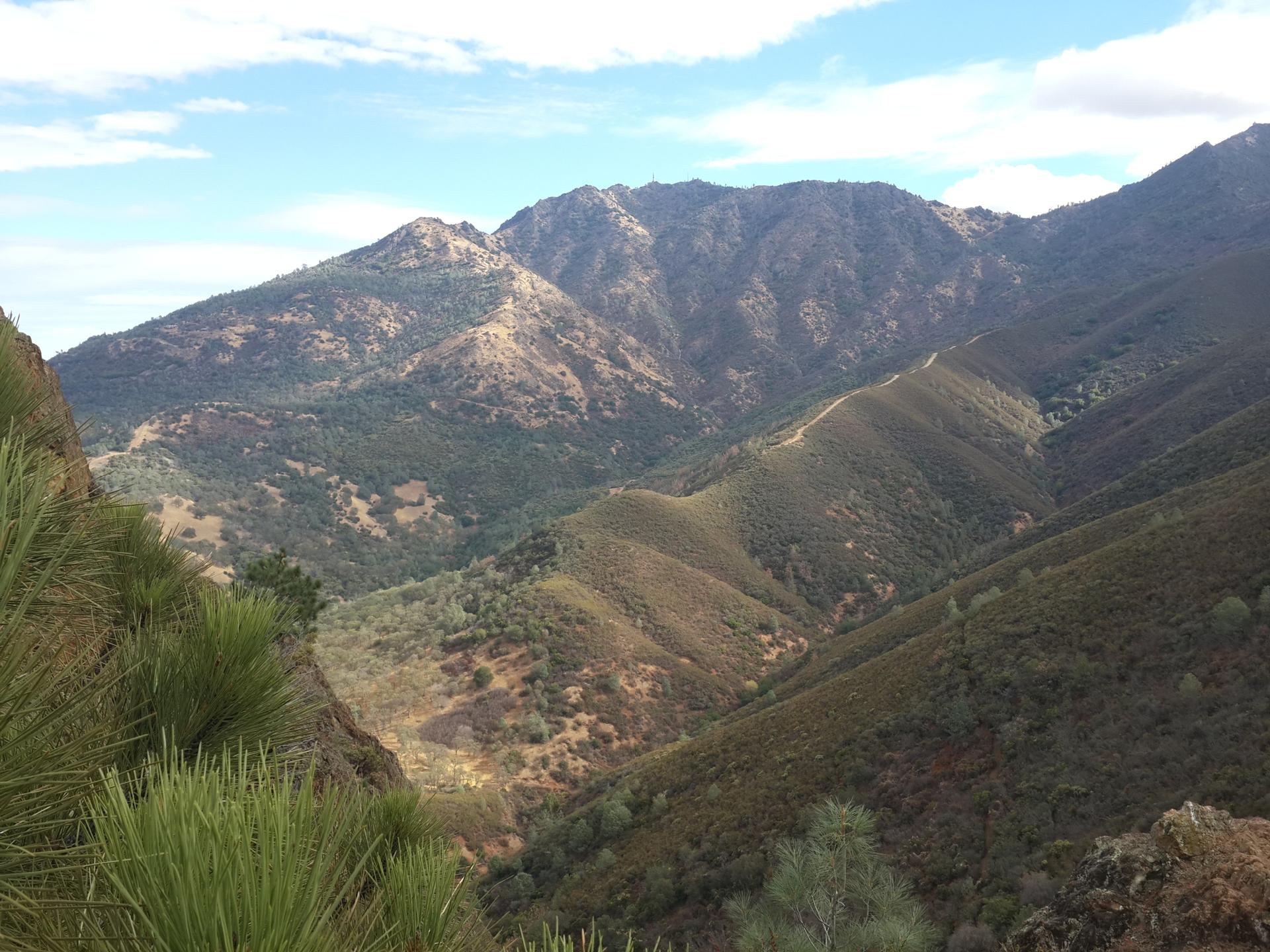 Deep valley with forested mountains and ridges under a partly cloudy sky.