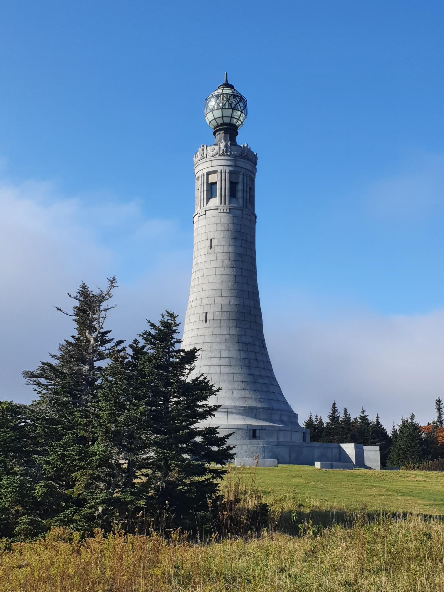 A tall, ornate stone tower with a glass top against a blue sky.