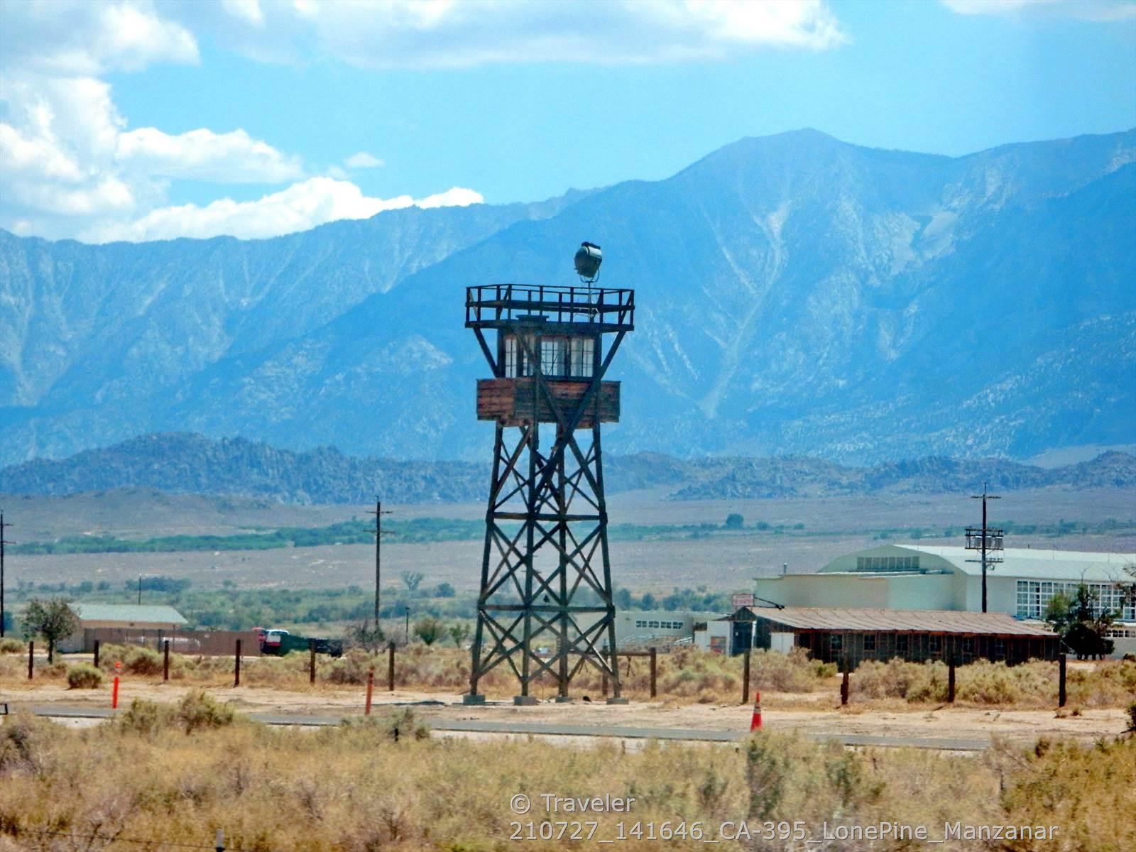 A tall watchtower stands in a desert landscape with distant blue mountains.