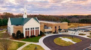 Aerial view of a large church and adjacent building under a cloudy sunset sky.