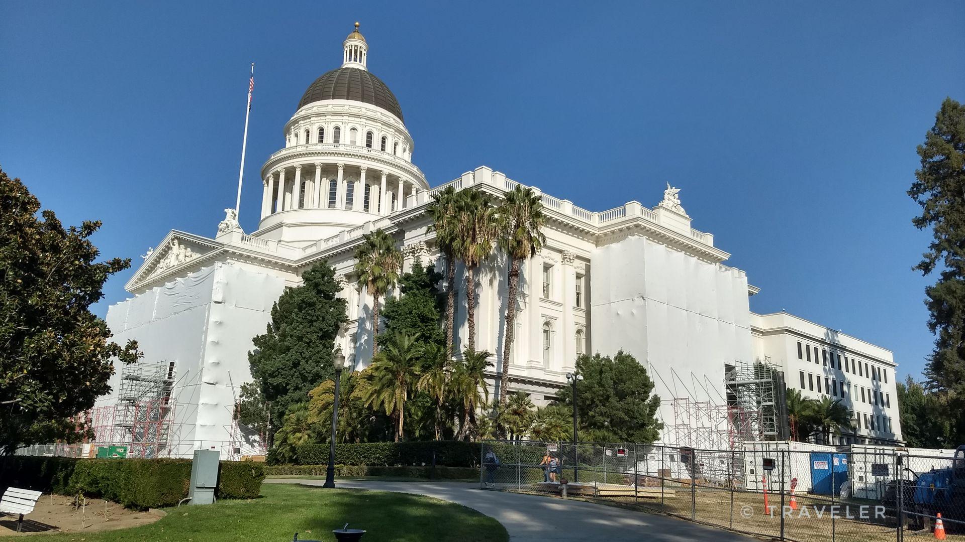 White domed building partially covered in scaffolding, surrounded by trees.