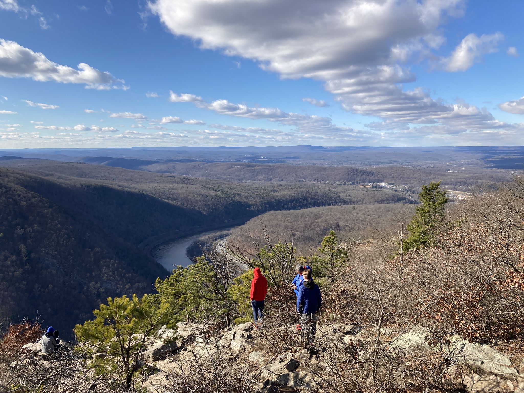 People on a mountain overlook with a vast forested valley and river below on a bright day. - Mount Tammany and Sunfish Pond Loop