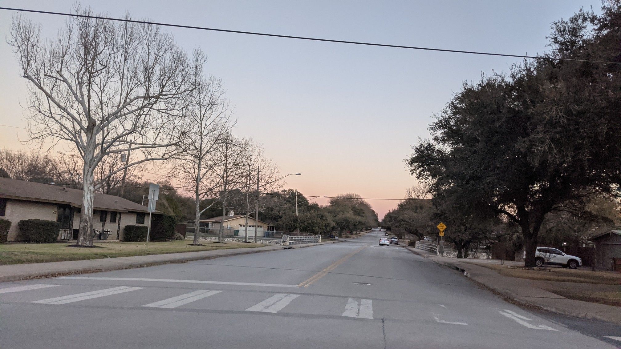 A quiet street with bare trees and houses under a soft, warm sky. - Mesa Drive – Rolling hills up to Round Rock loop from Crestview