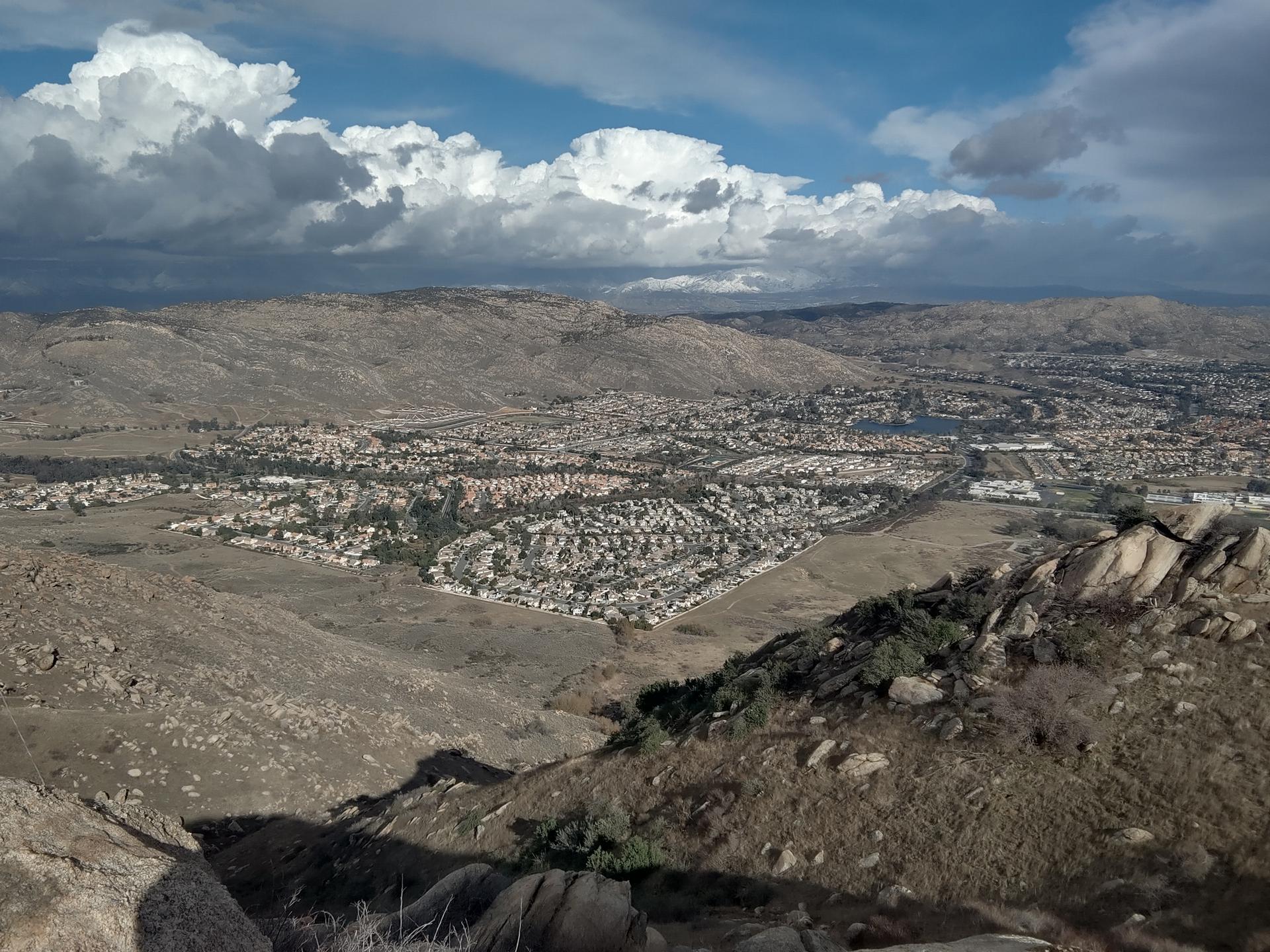 Overhead view of a town nestled in a dry, hilly valley under cloudy skies.