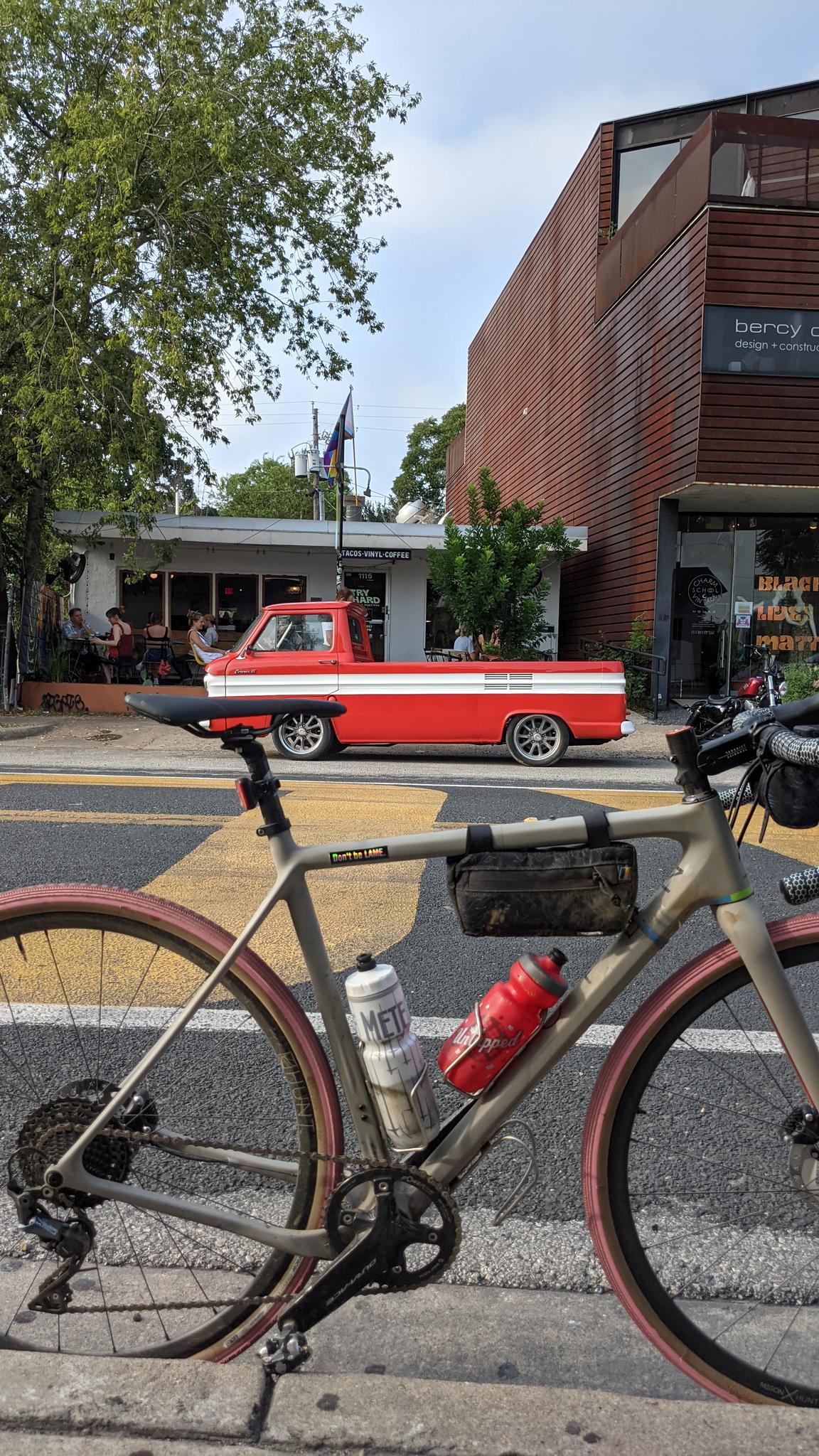 Bicycle parked on street with a red vintage truck and buildings.