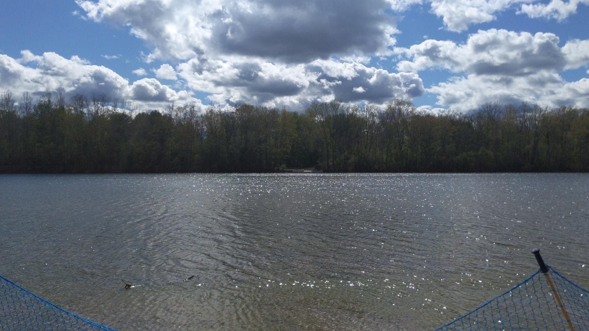 Wide lake with distant forest under a partly cloudy sky.