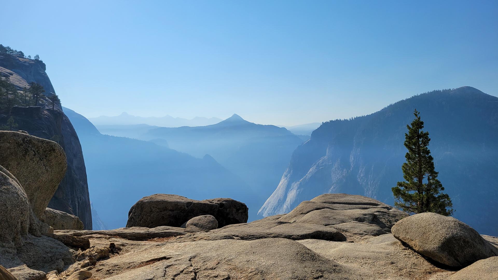 Hazy blue mountain peaks and a valley under a clear sky.