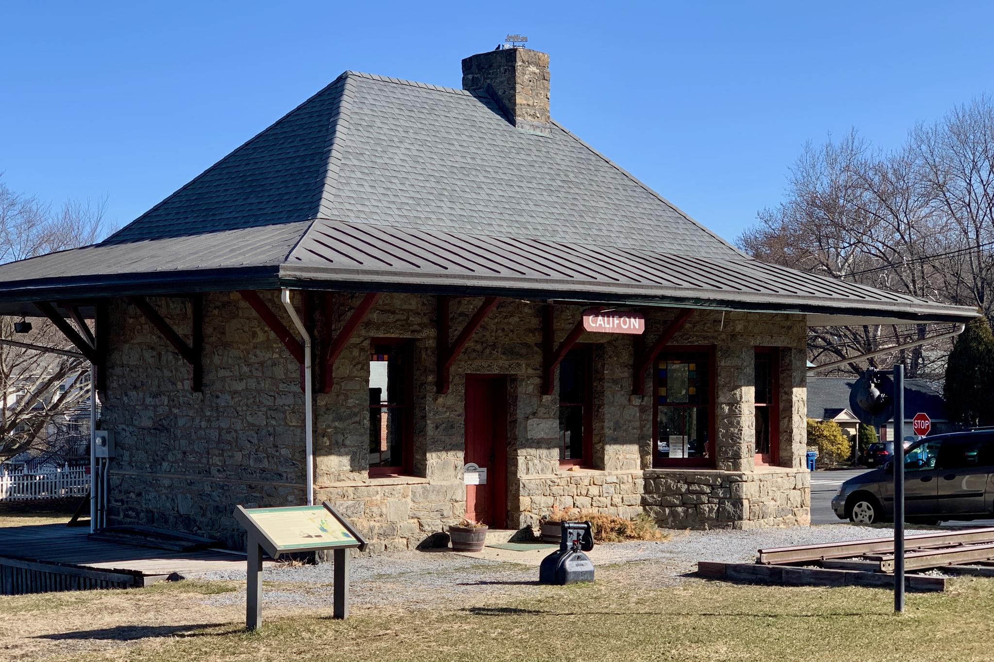 A small stone building with a gray roof under a clear blue sky.