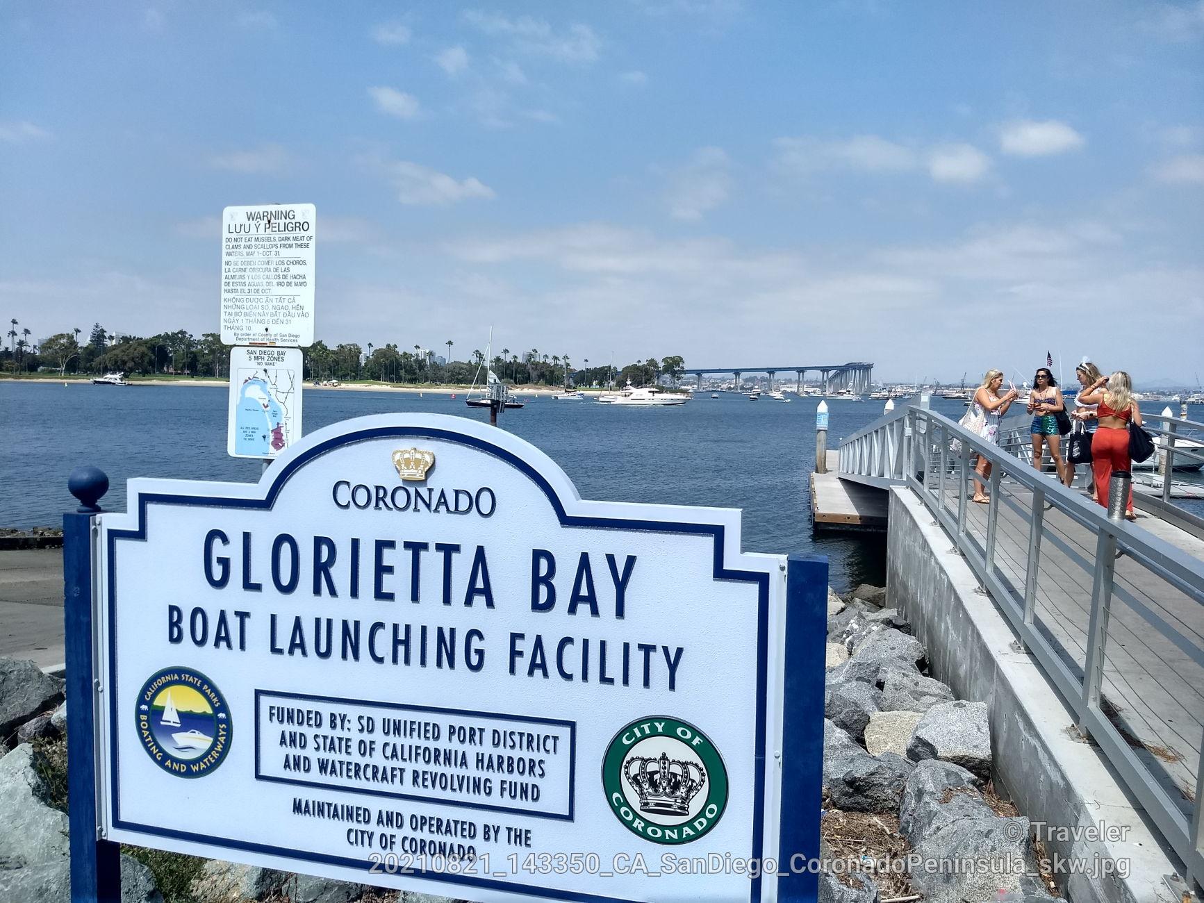 Sign for a boat facility, with people on a pier and boats on blue water.
