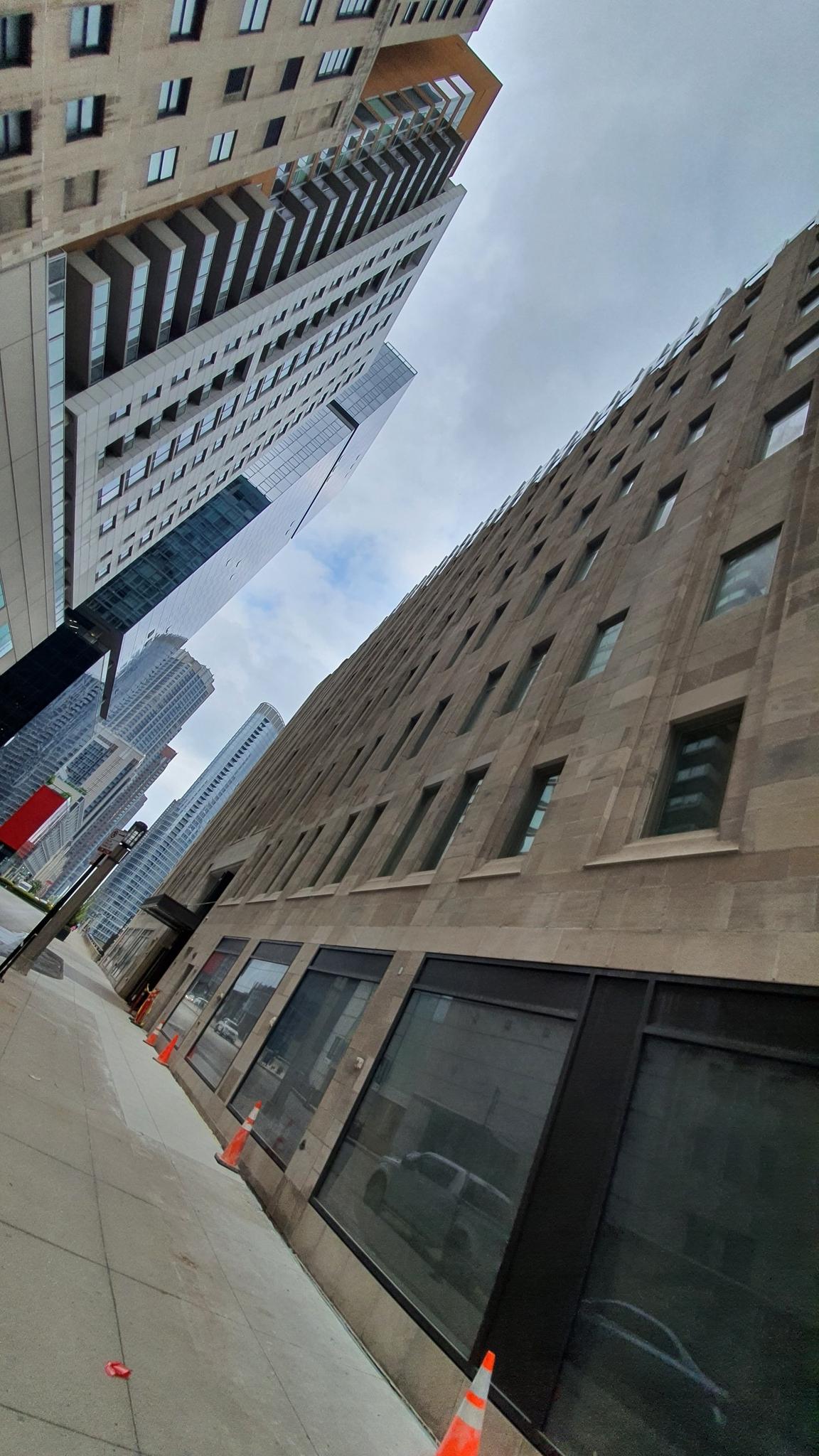 Angled view of tall city buildings with a street and construction cones.