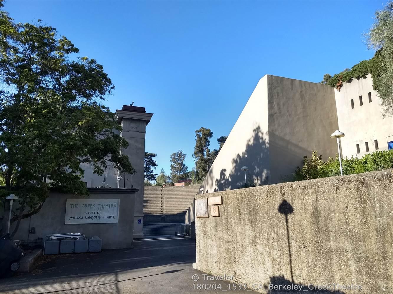Modern, angular concrete building with trees under a bright blue sky.