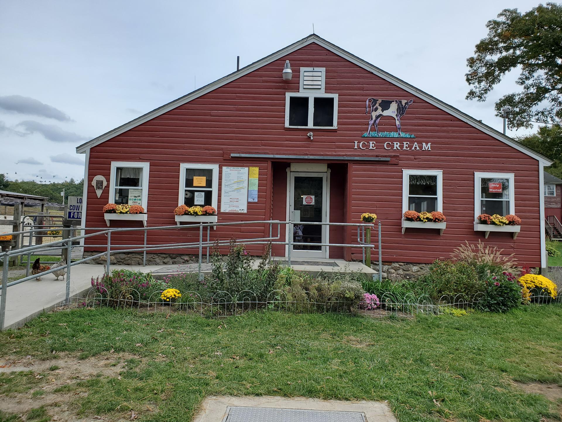 A red ice cream shop building with flower boxes under an overcast sky.