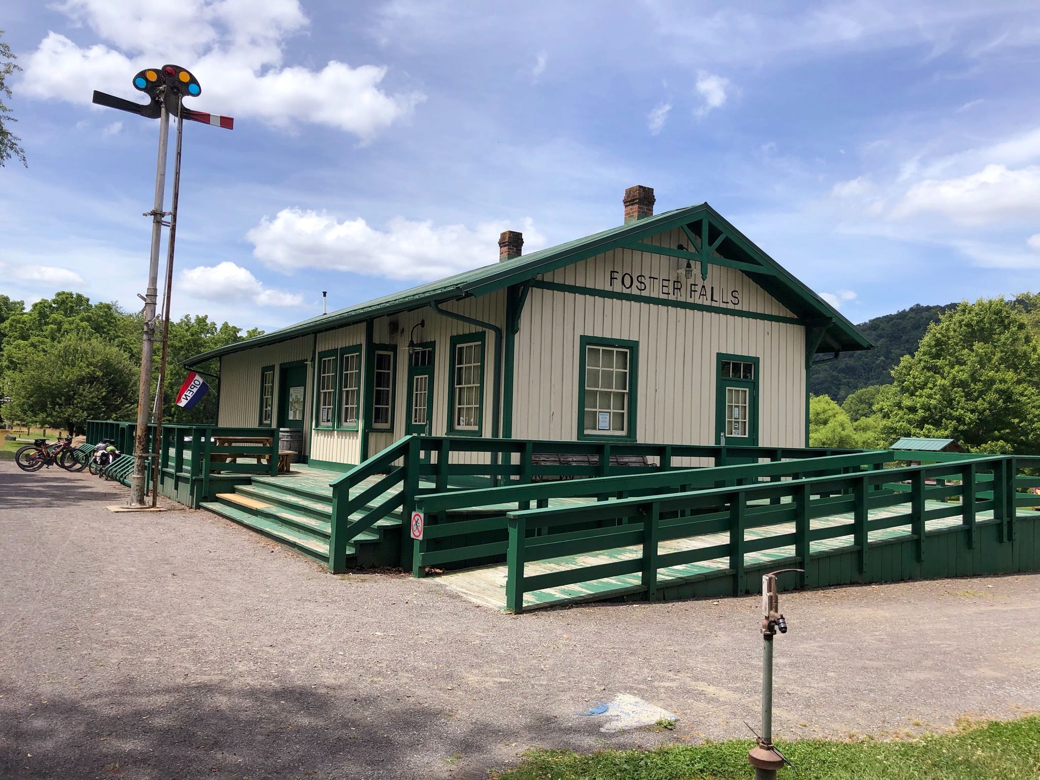 White and green building with a ramp under a bright, cloudy sky, bicycles parked. - Foster Falls – Fries Junction loop from Fries