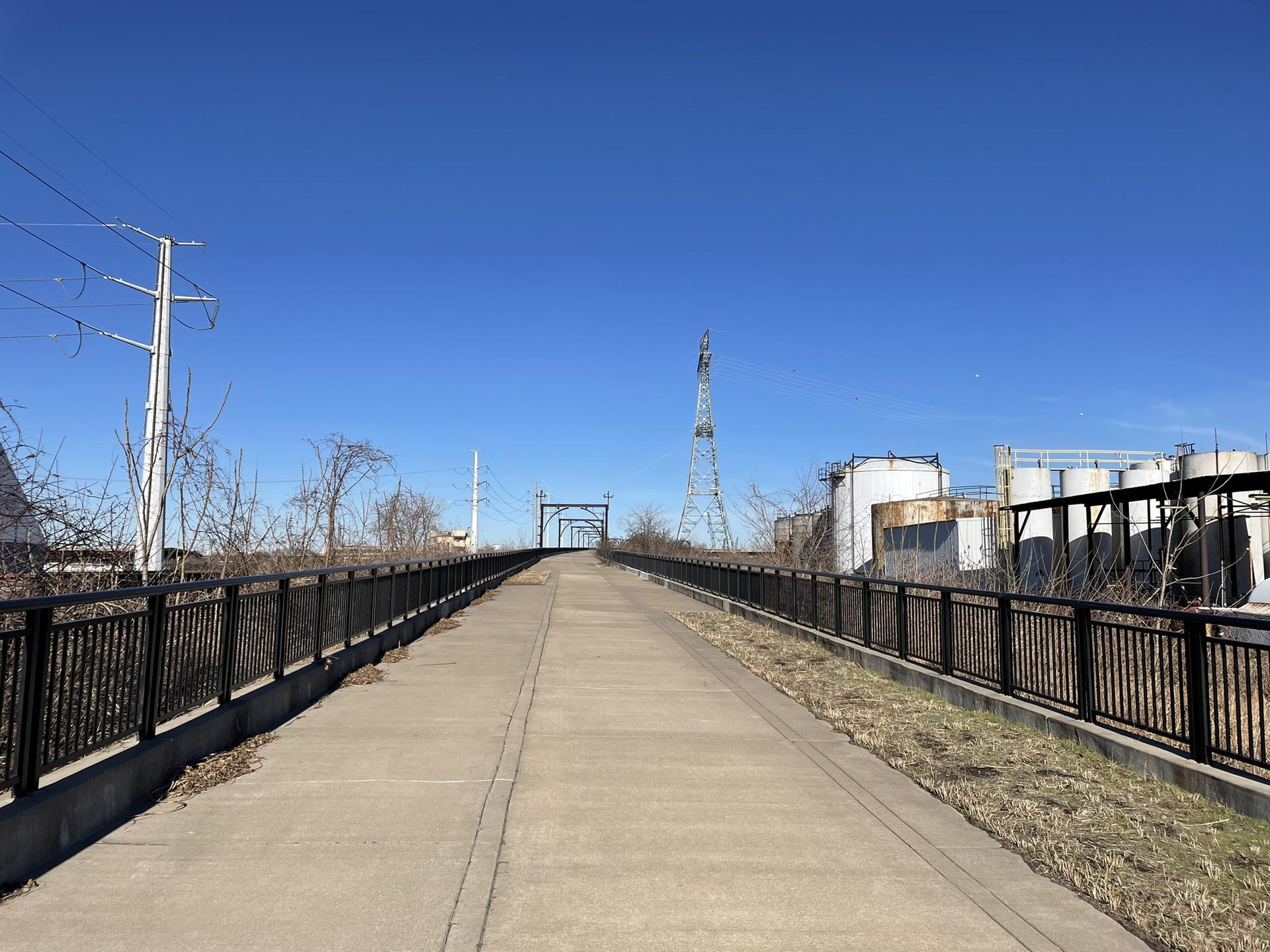 A long, elevated paved path leads towards industrial structures.