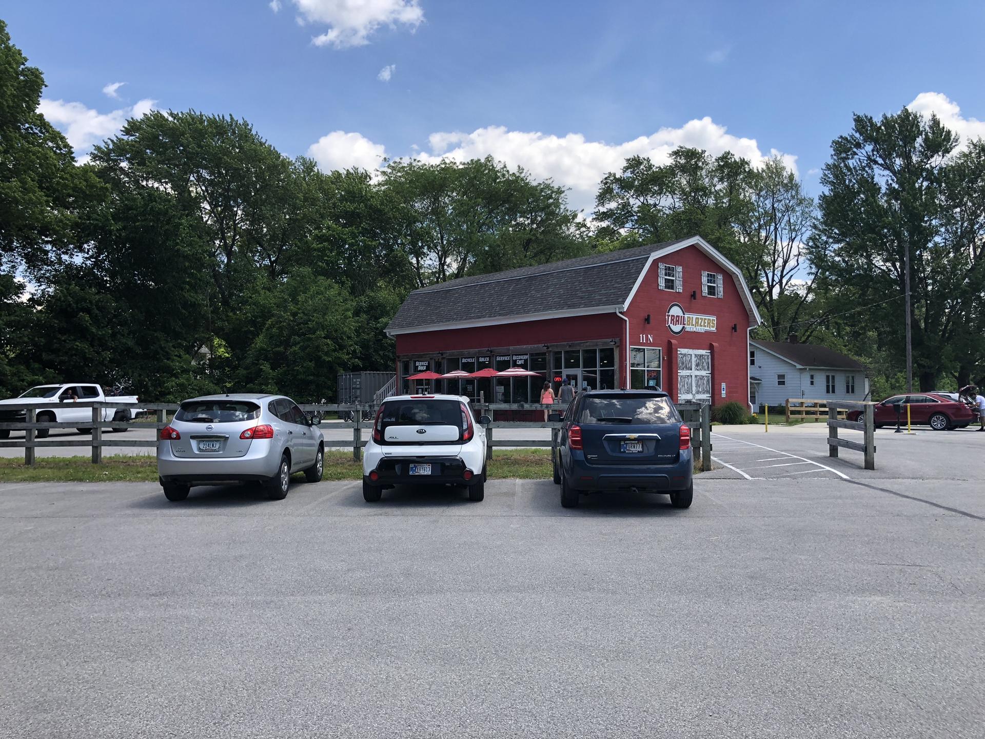 Red barn-like building with parked cars in front on a sunny day.