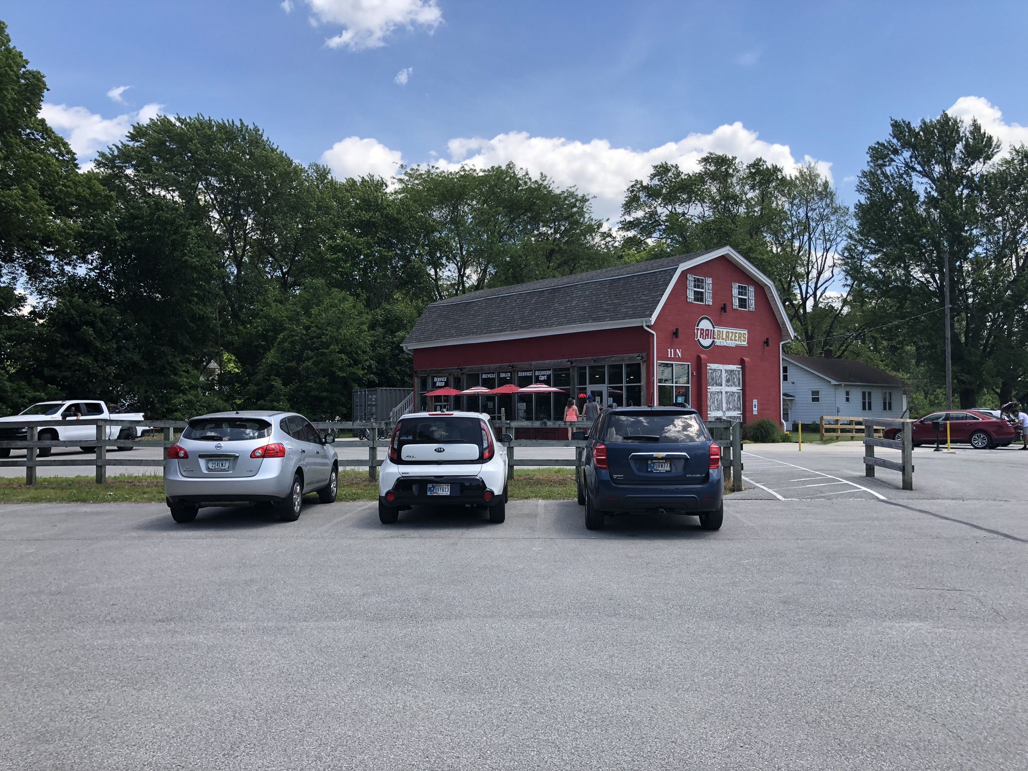 Red barn-like building with parked cars in front on a sunny day. - Trailblazers Bike Barn loop from Porter