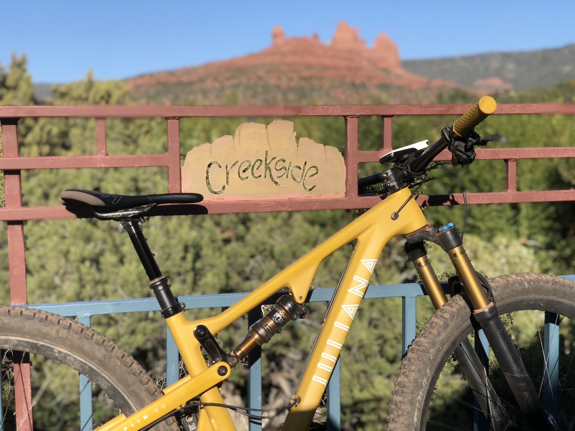 Yellow mountain bike in front of a wooden fence with a red rock formation.
