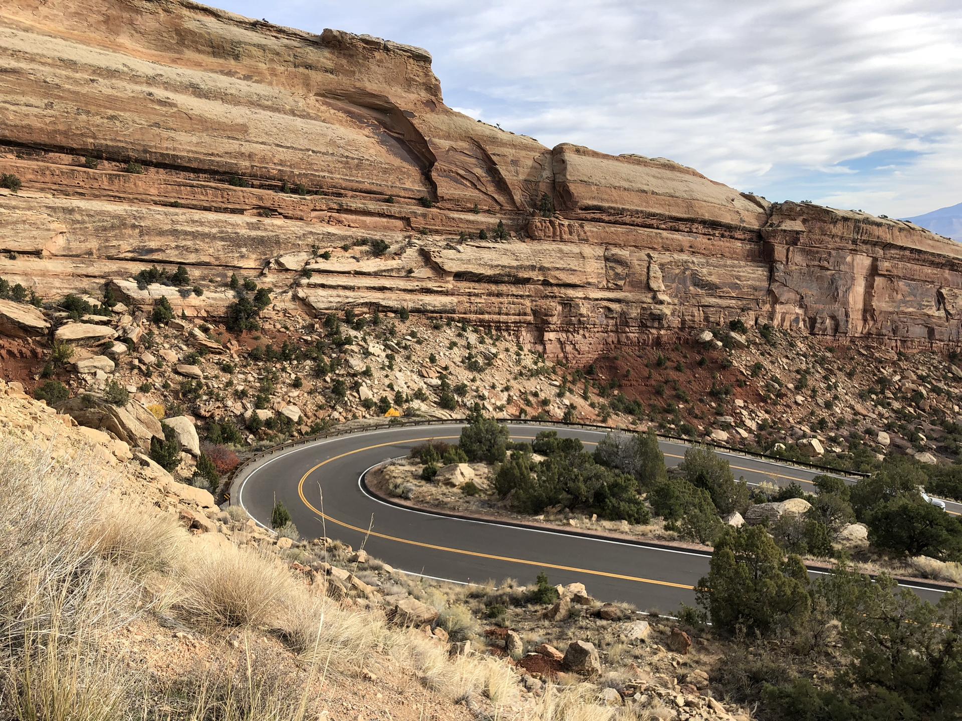 A winding road curves through a dramatic red rock canyon.