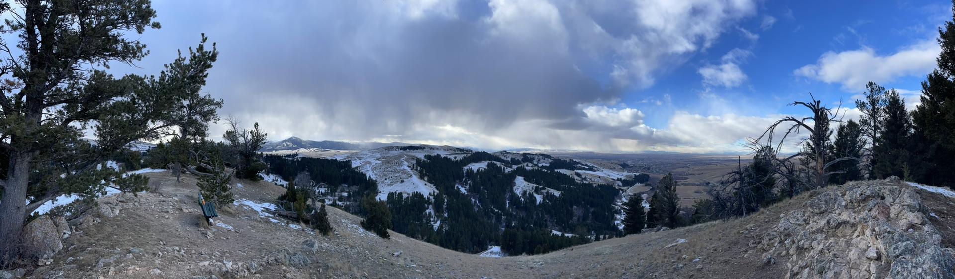 Panoramic view of a snow-dusted mountain landscape under a cloudy sky.