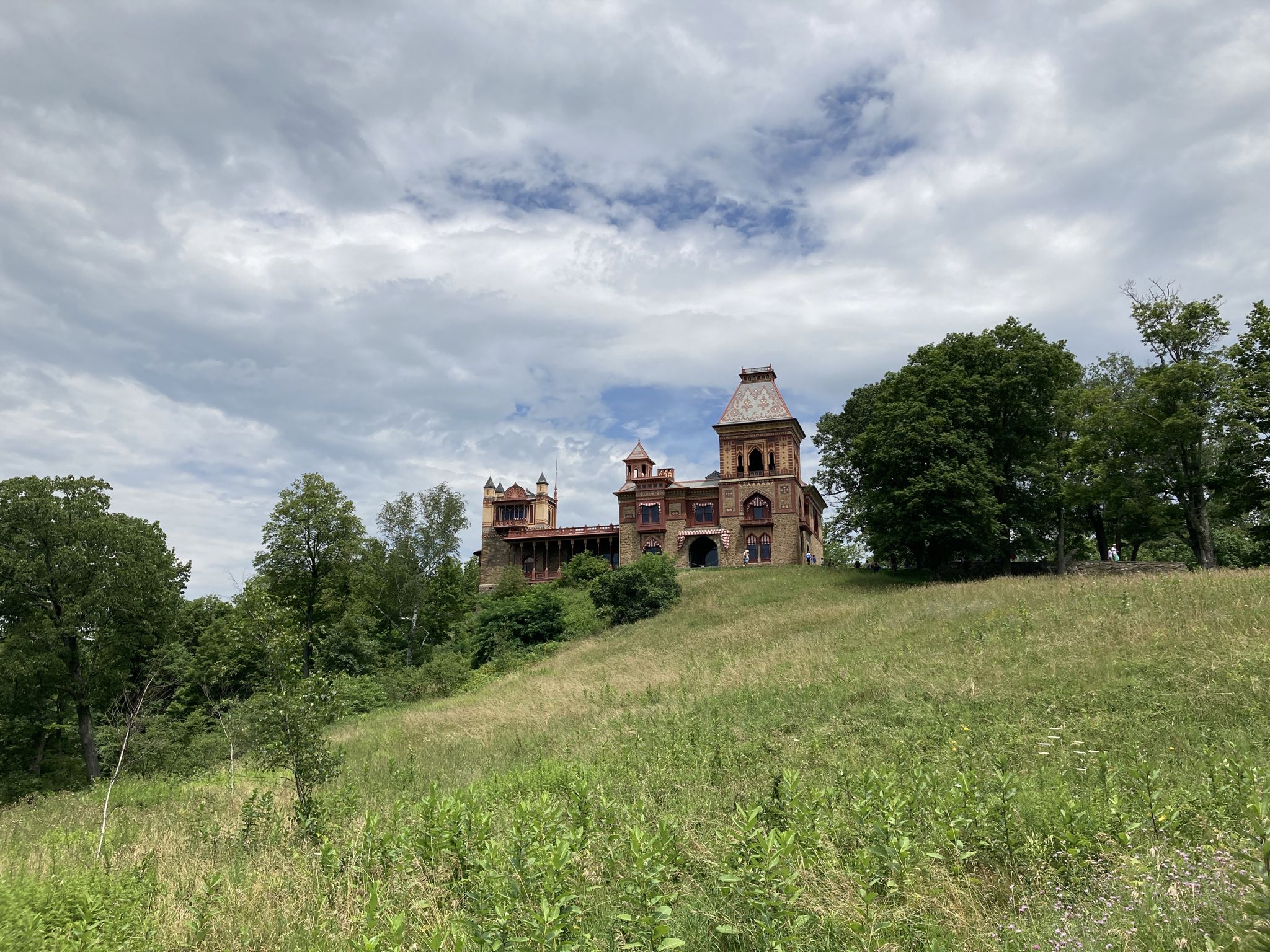 Ornate historic building on a grassy hill under a cloudy sky. - Hudson River Skywalk Loop
