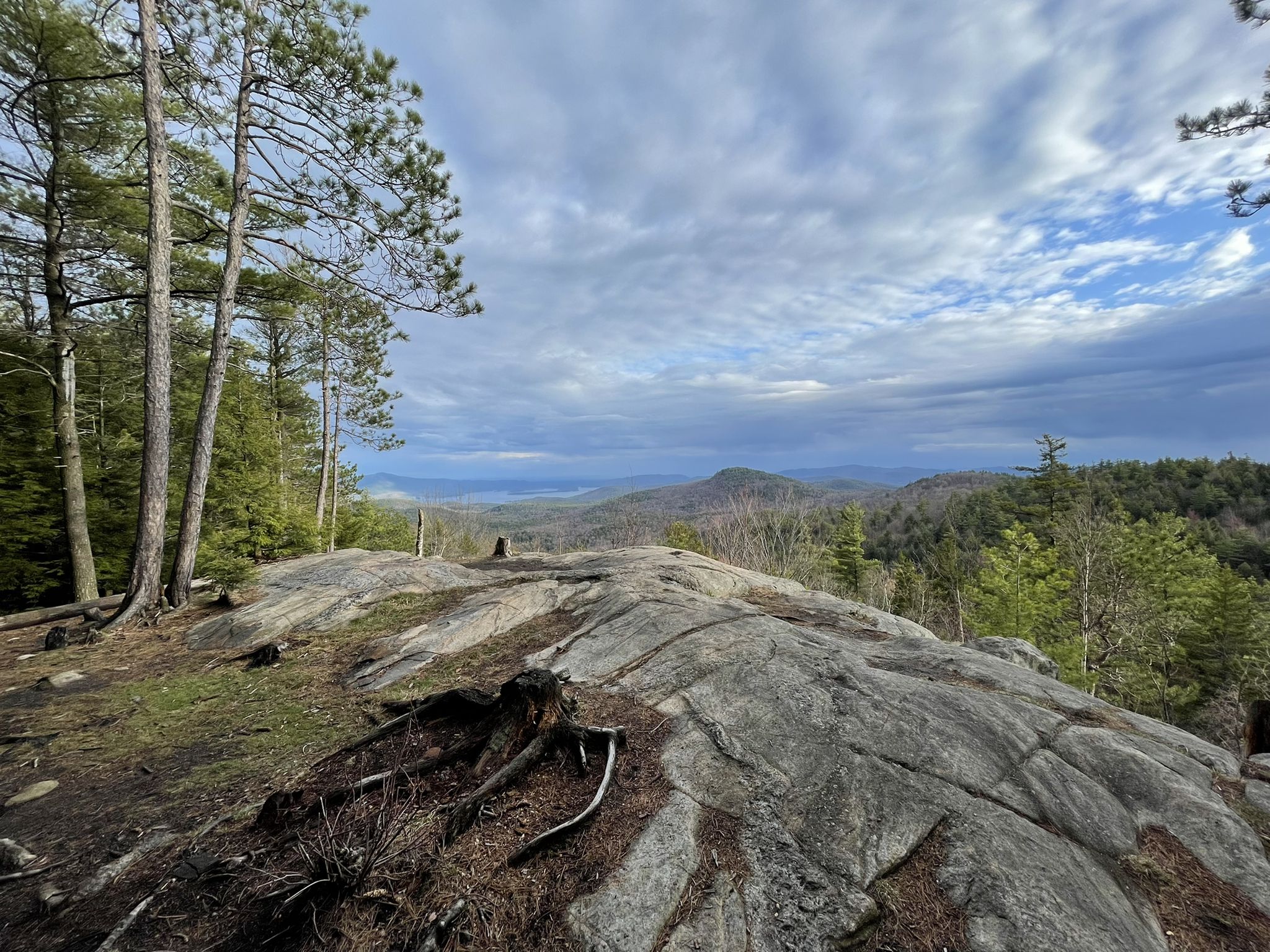 Rocky ground overlooks a vast forested valley under a cloudy sky. - Cat and Thomas Mountain Loop