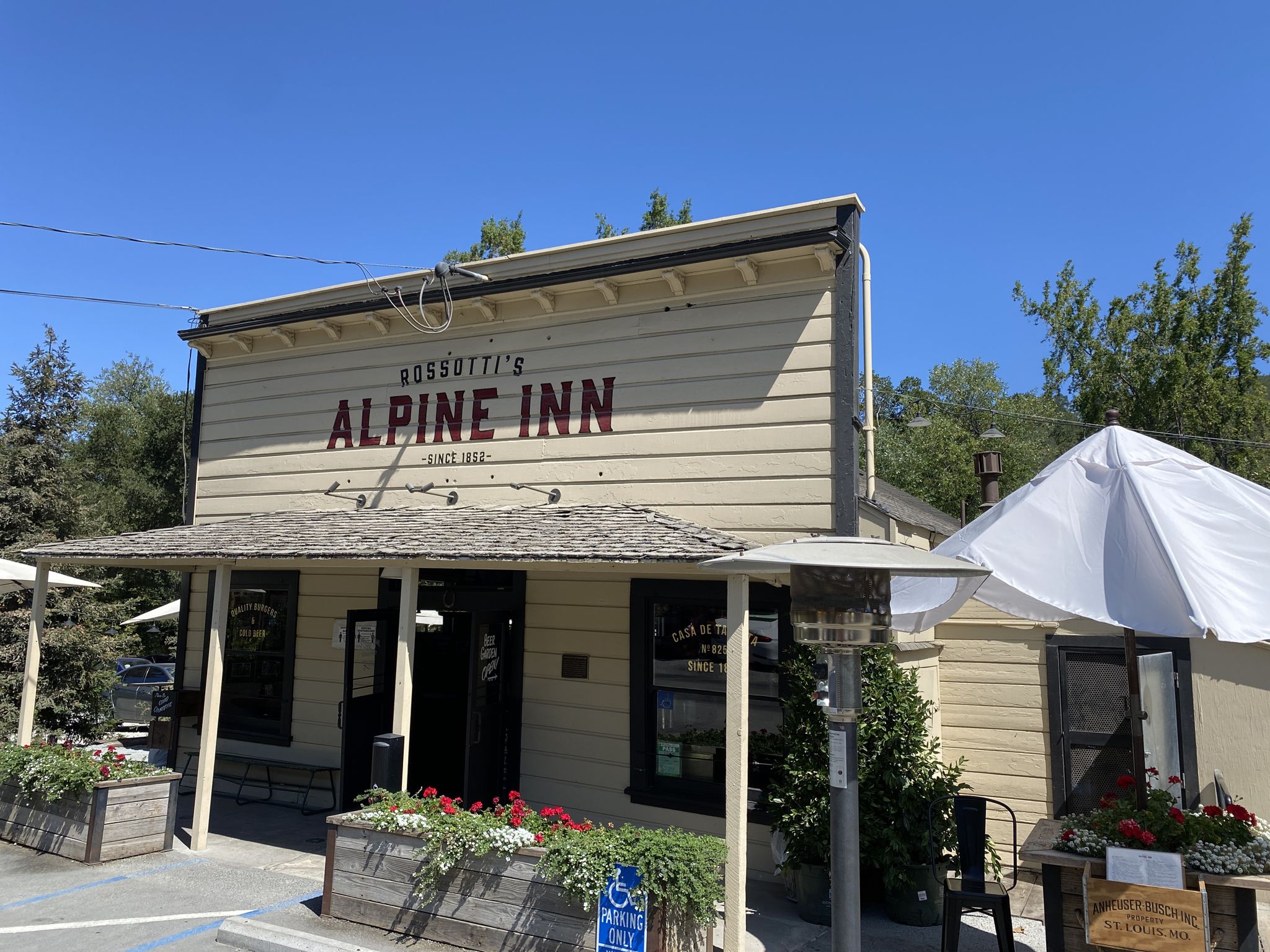 Rustic 'Alpine Inn' building with outdoor seating and a white umbrella. - Rossotti's Alpine Inn – Dwight Crowder Path loop from Los Trancos Open Space Preserve