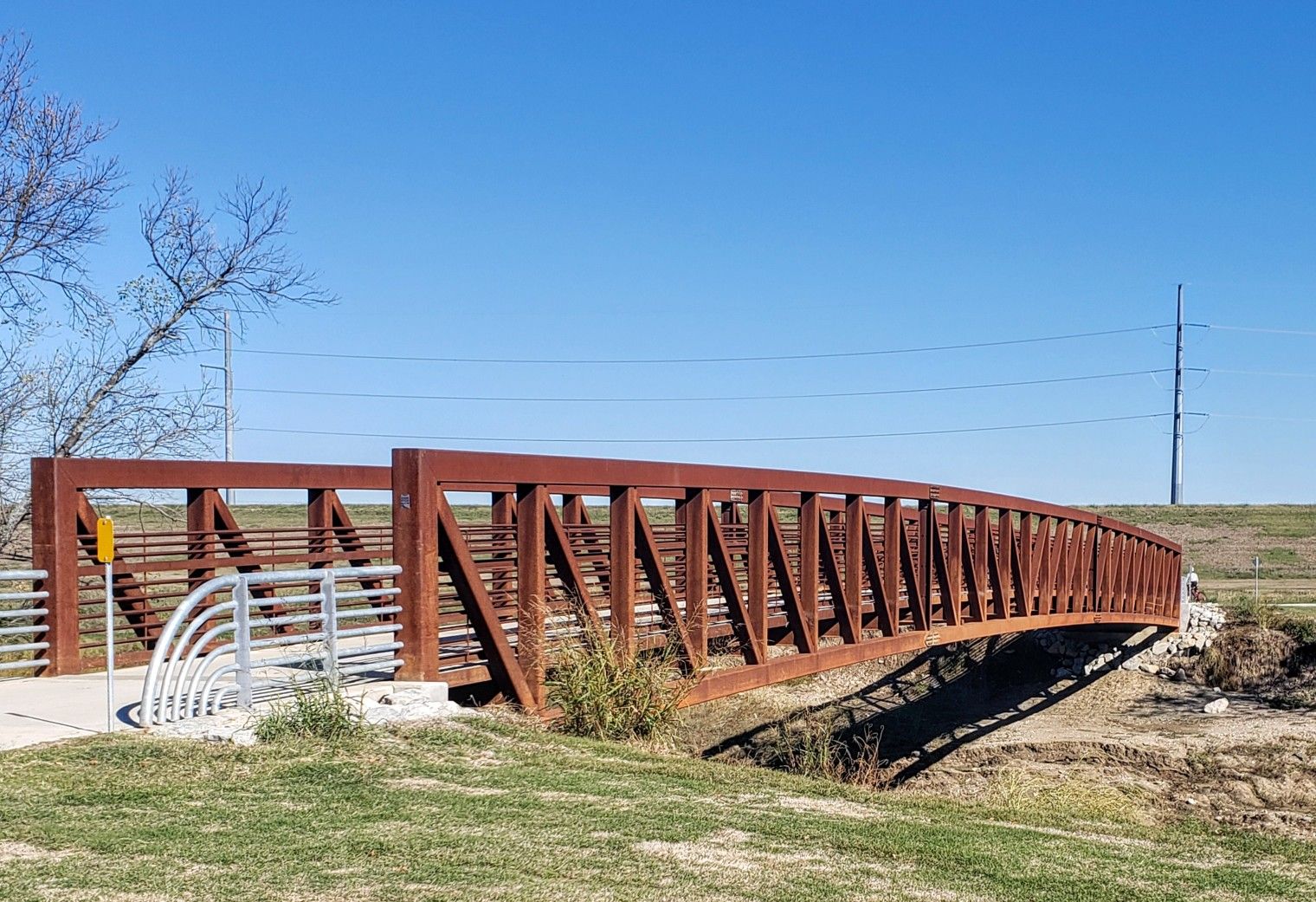 A long, curved, rusty brown metal bridge under a clear blue sky. - Union Station to New Bridge over Elm Fork of Trinity River loop