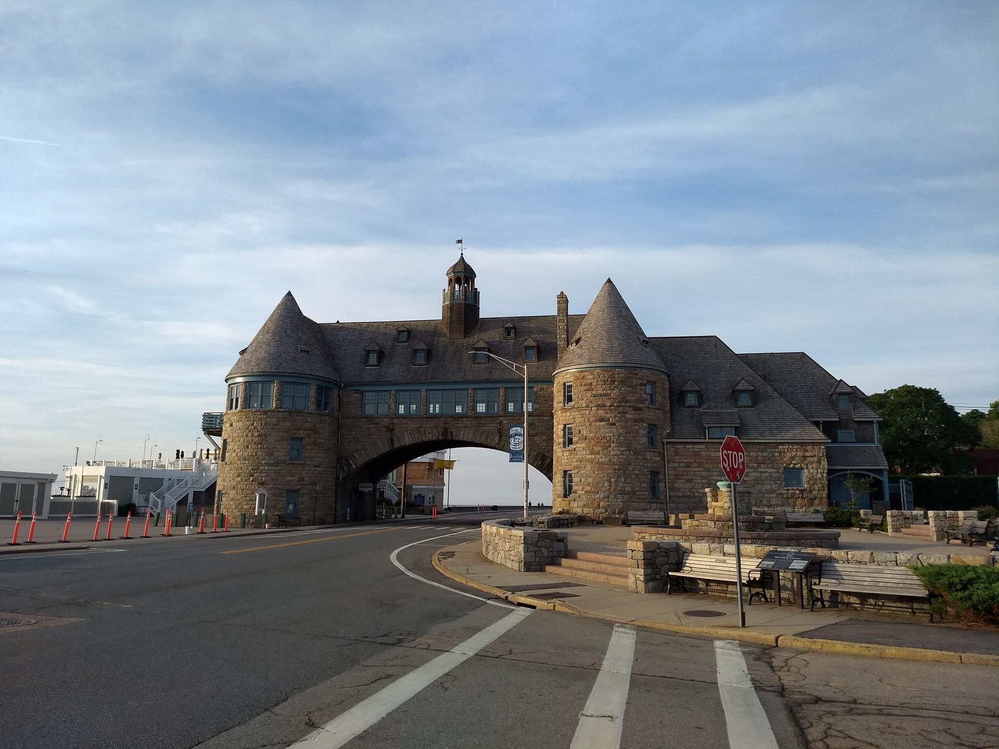 A large stone building with an archway over a road on a cloudy day.