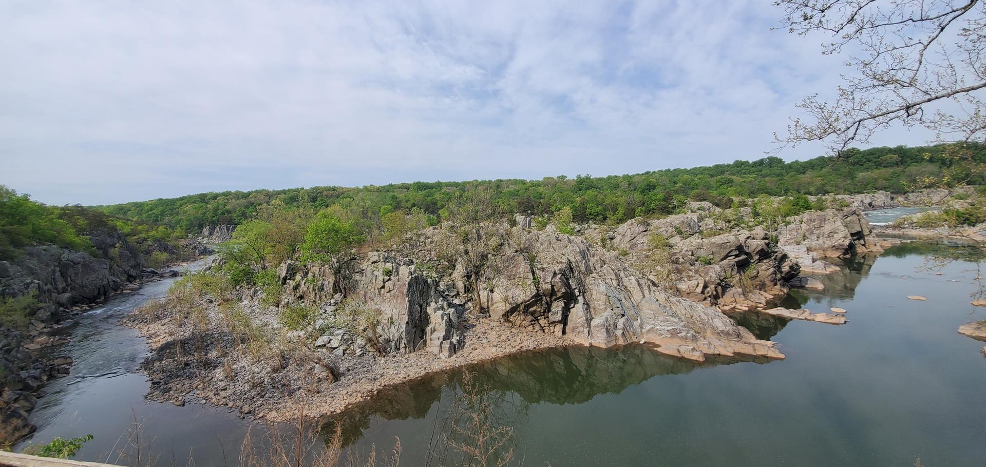 A wide river with rocky islands and forested banks under an overcast sky.