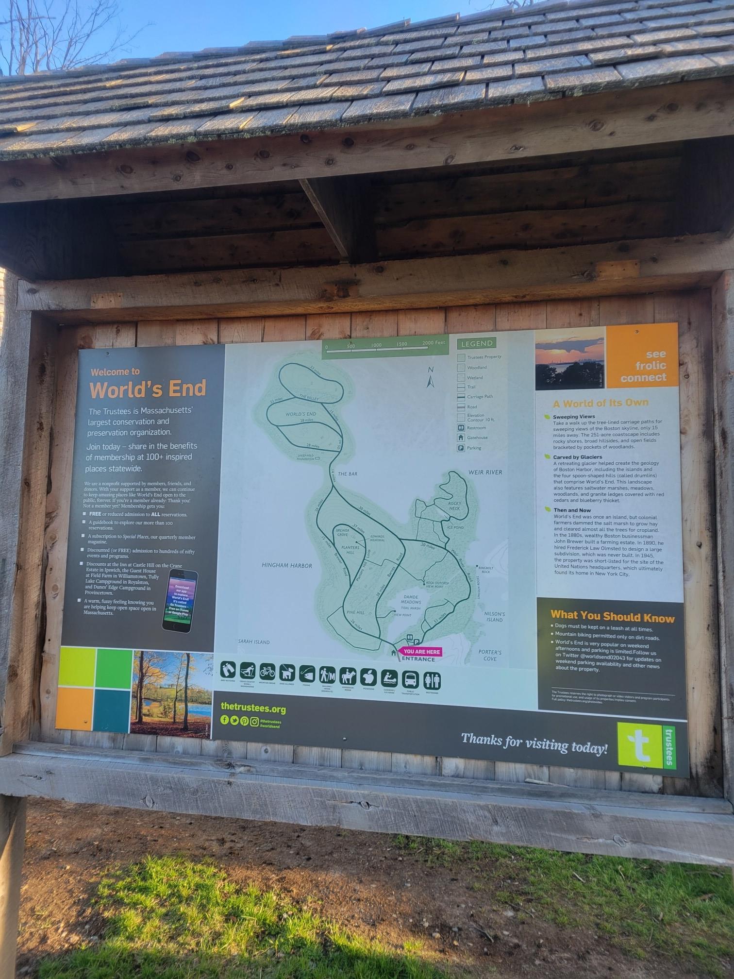 A wooden information board displays a trail map in bright sunlight.