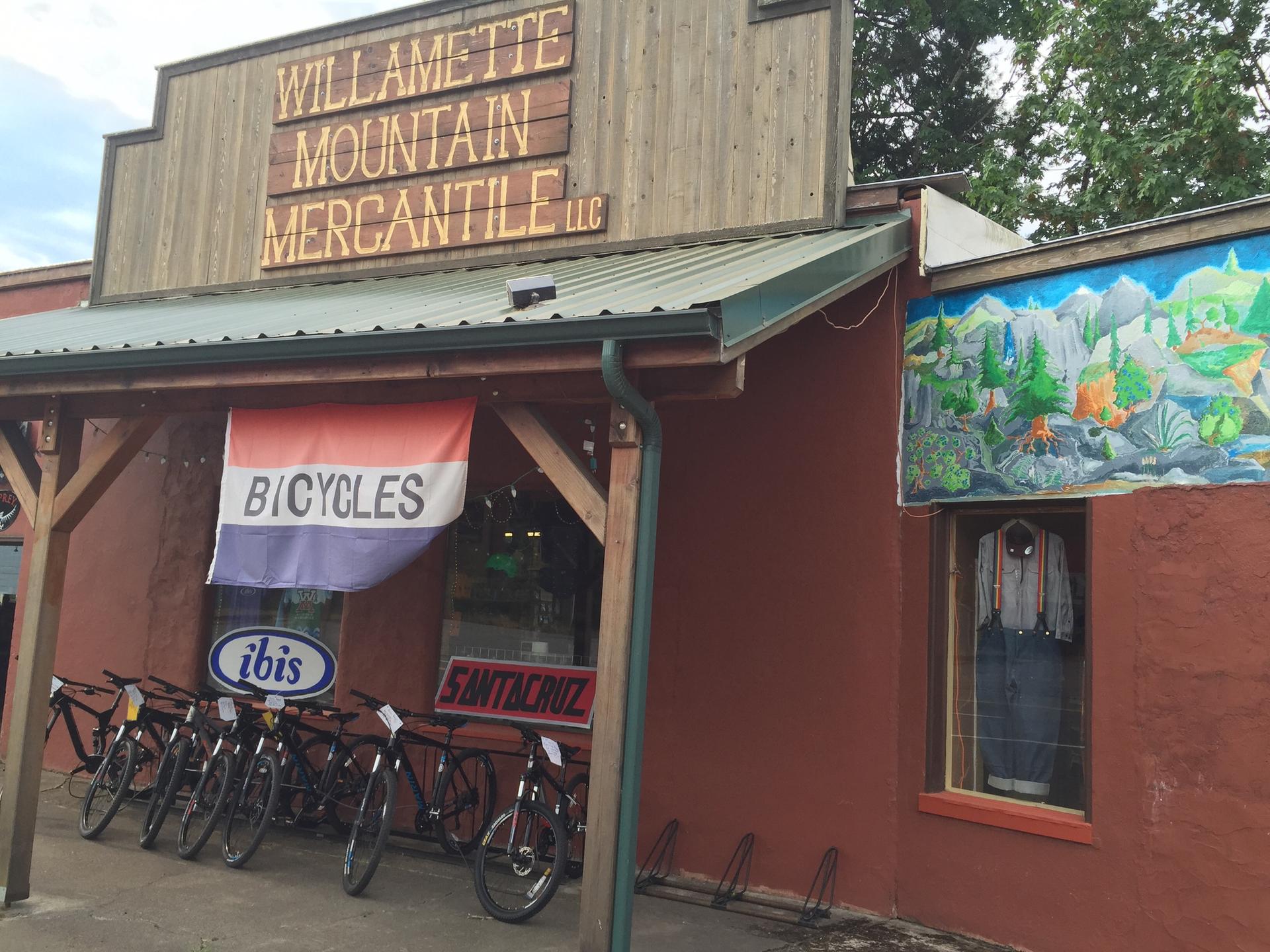 Storefront with bicycles for sale under a wooden awning on an overcast day.