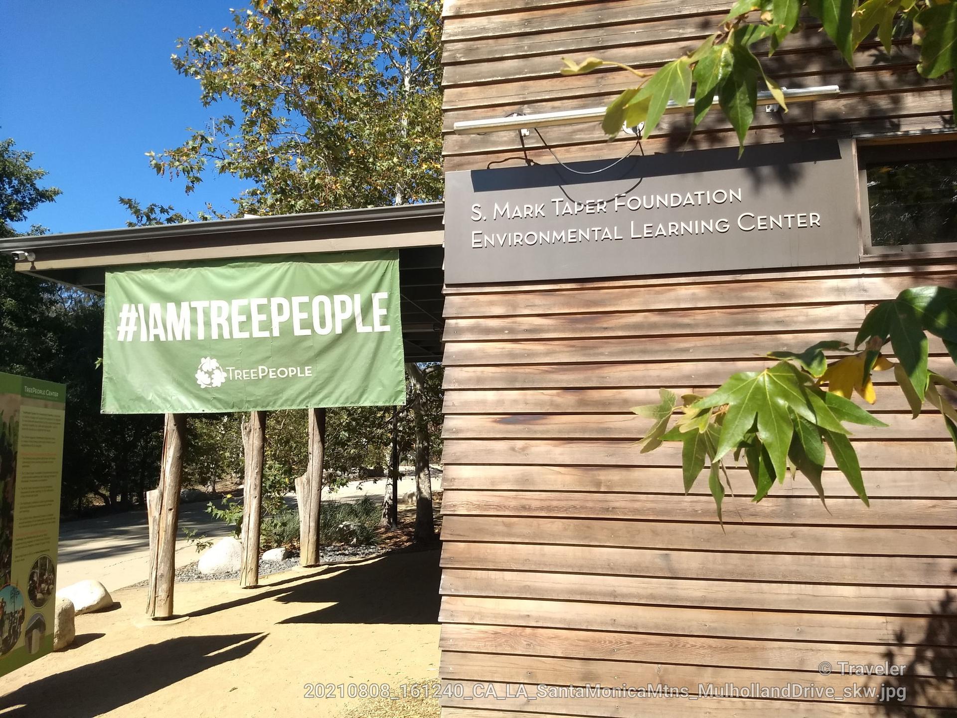 A wooden building with an environmental learning center sign and a green banner.