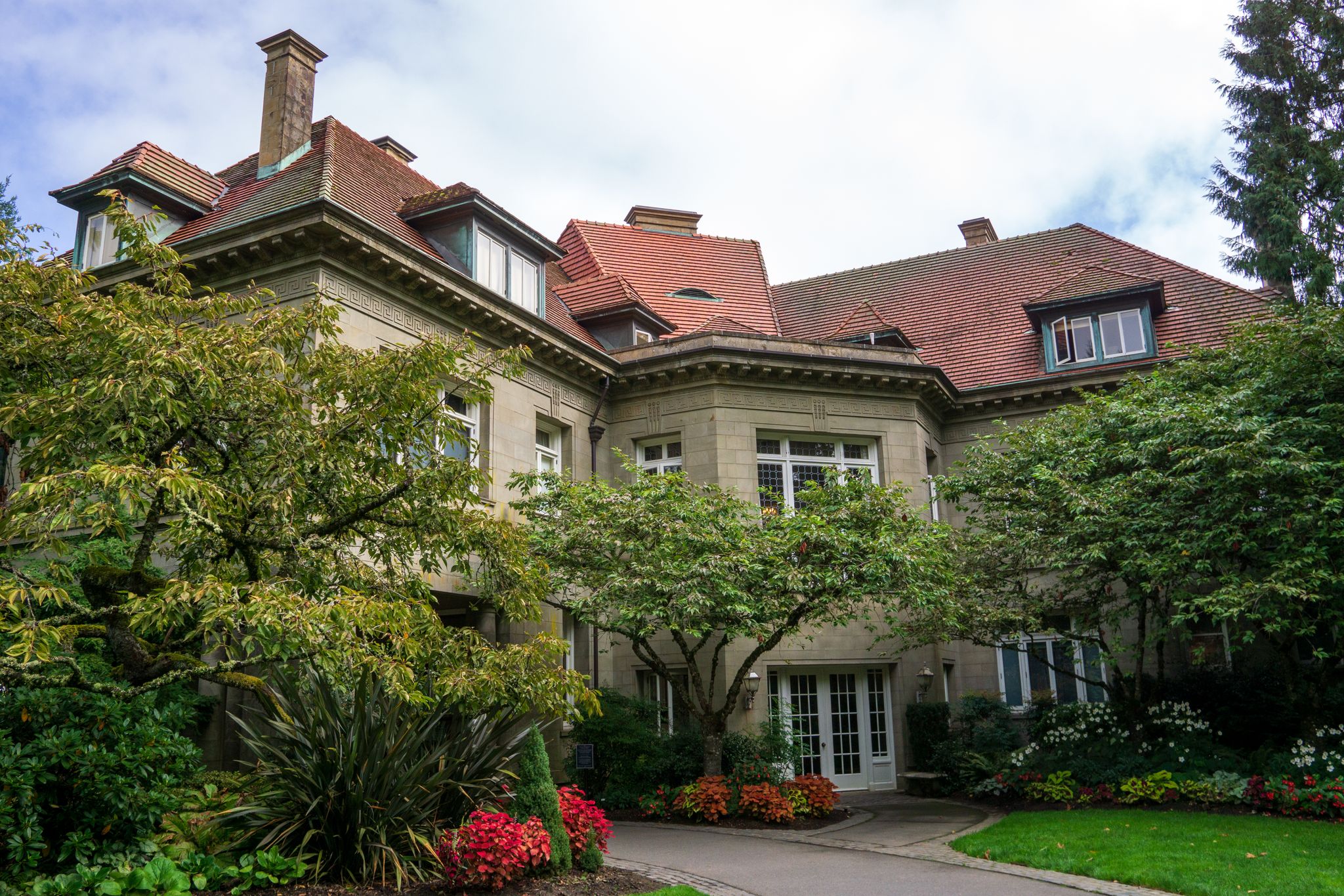 Ornate stone mansion with red tile roof, surrounded by lush green landscaping. - Lower Macleay and Wildwood Trail to Pittock Mansion